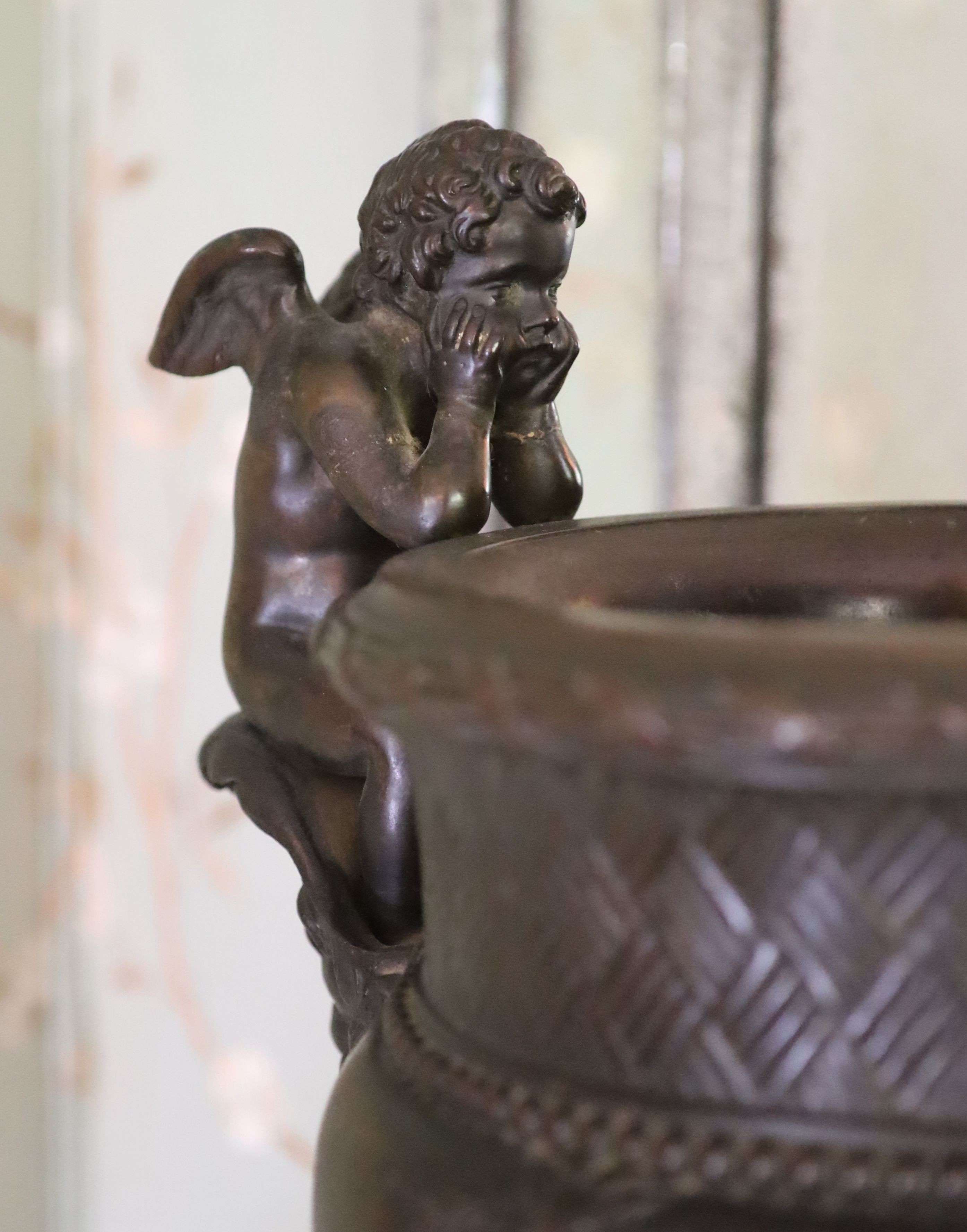 A classical style bronze urn modelled with disconsulate cherubs, height 44cm width 40cm